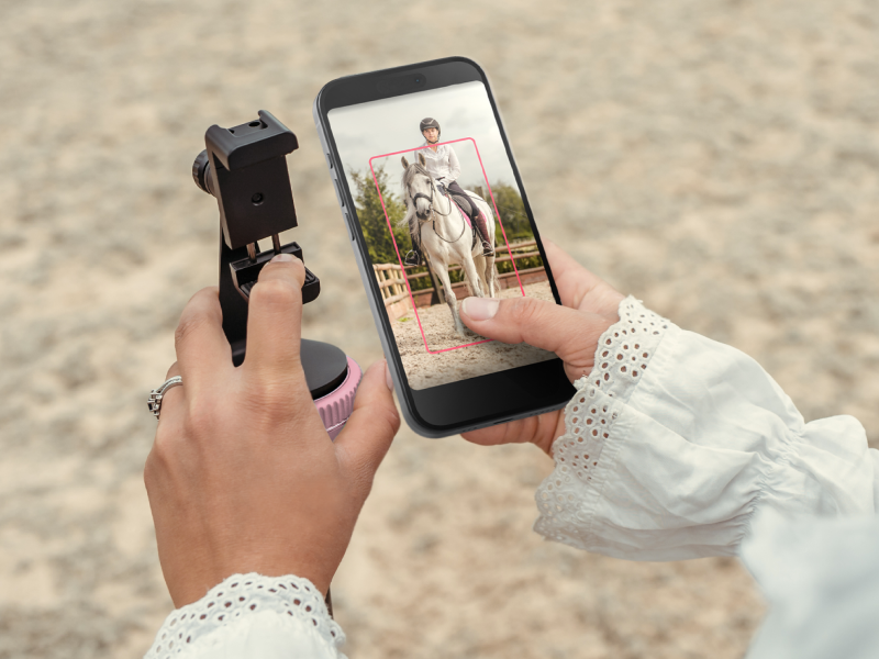 Purple auto-tracking phone holder with 360° rotation mounted on stand, showing remote control and tracking indicators — view 7a